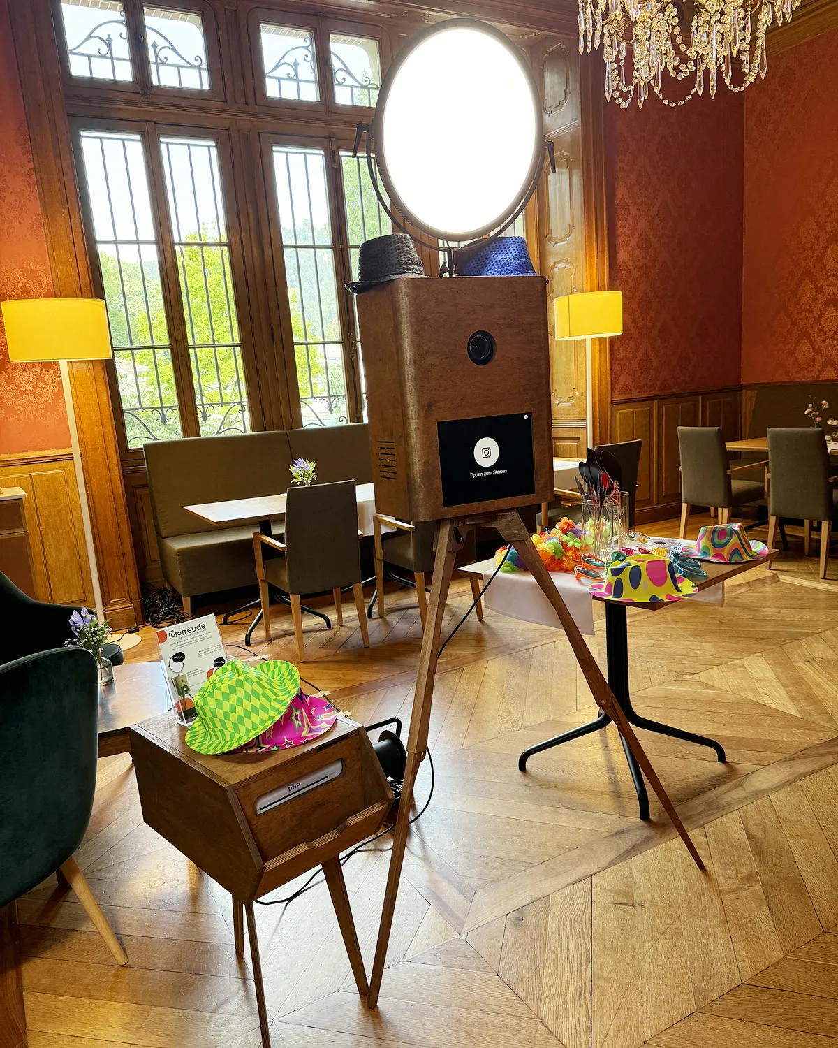 Fotobox Pro mit rundem Ringlicht und Druckerhocker in einem Festsaal mit Kronleuchter